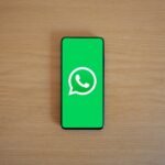 Um smartphone exibindo o logotipo do WhatsApp com um cadeado e um símbolo de proibição, ilustrando o risco de banimento.